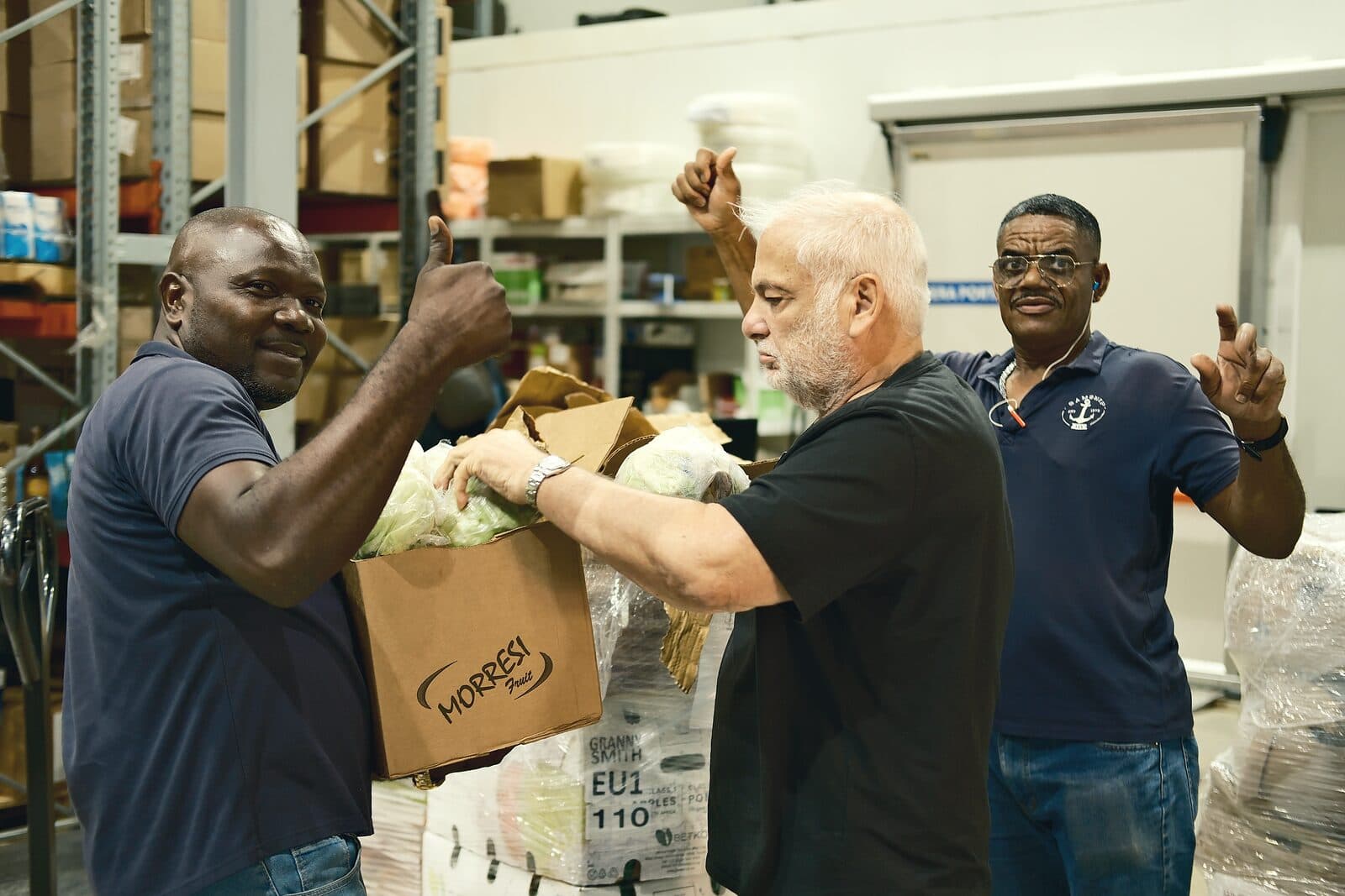 Three Samship colleagues packing a box of produce together in the warehouse