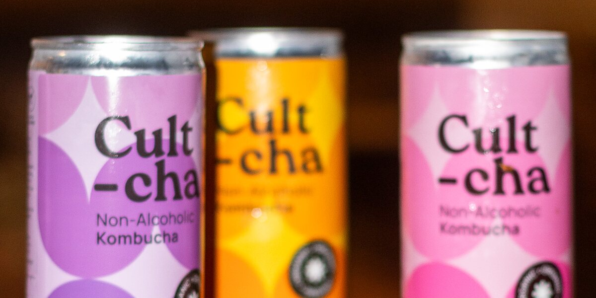 Three cans of Cultcha kombucha on a wooden counter